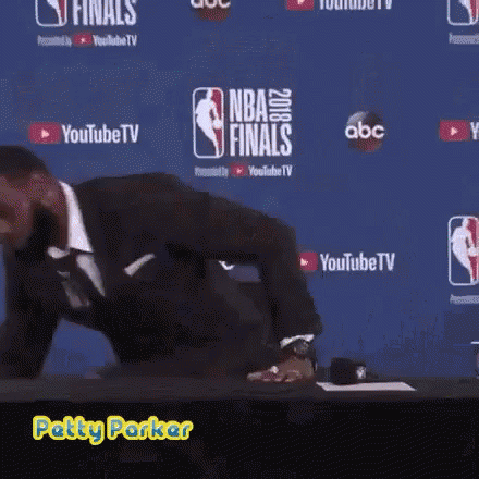 a man in a suit is standing in front of a wall that says nba finals on it