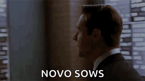 A Man In A Suit Is Standing In Front Of A Window With The Words Novo Sows Written On The Screen . GIF