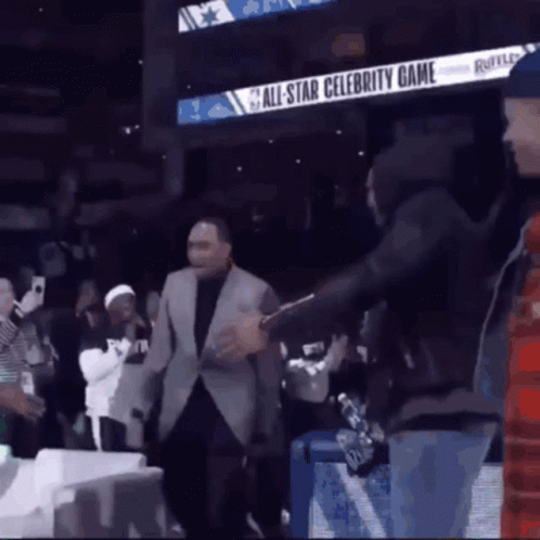 A Man In A Suit Is Standing In Front Of An All Star Celebrity Game Sign GIF