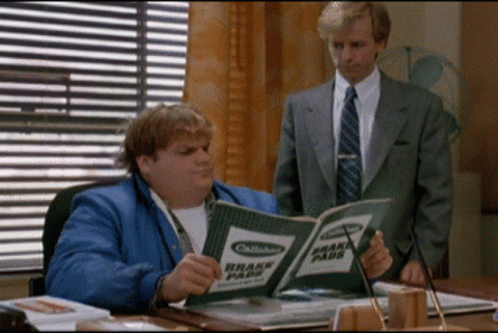 A Man In A Suit Is Standing Next To A Man Reading A Book Titled Brake Pads GIF