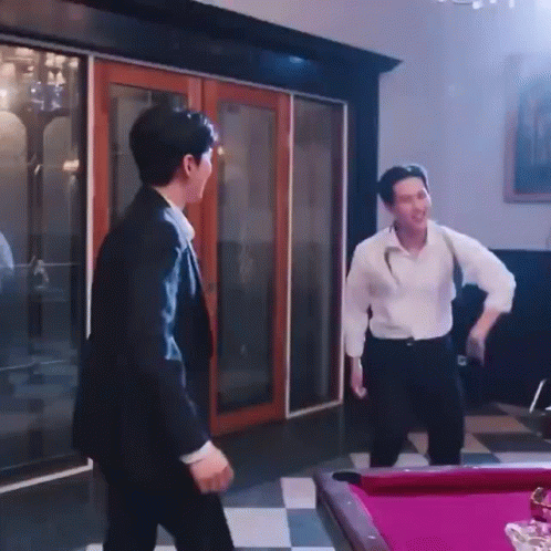 A Man In A Suit Is Standing Next To A Pool Table . GIF