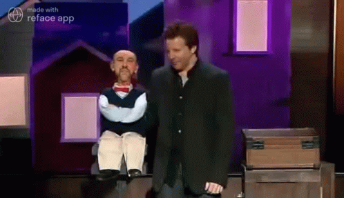 A Man In A Suit Is Standing Next To A Puppet . GIF
