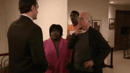 A Man In A Suit Is Standing Next To A Woman In A Pink Jacket . GIF
