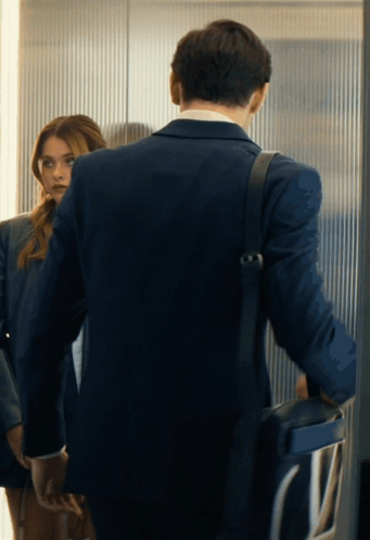 A Man In A Suit Is Standing Next To A Woman In A Suit GIF