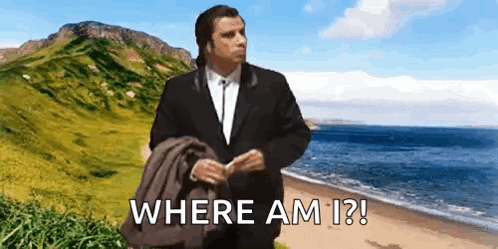 A Man In A Suit Is Standing On A Beach With The Words Where Am I ? Written Below Him GIF