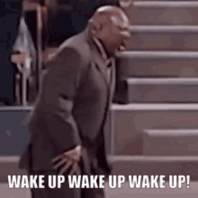 A Man In A Suit Is Standing On A Set Of Stairs And Says `` Wake Up Wake Up Wake Up '' . GIF