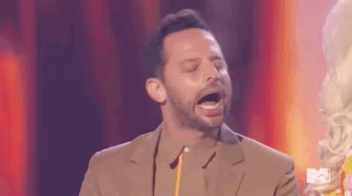 A Man In A Suit Is Standing On A Stage With His Mouth Open And Holding A Trophy . GIF