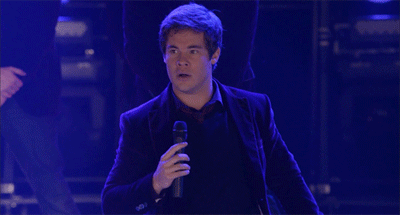 A Man In A Suit Is Standing With His Arms Outstretched GIF