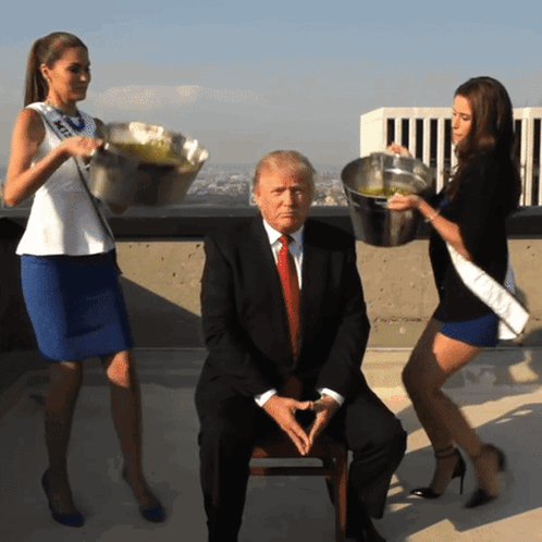 A Man In A Suit Is Surrounded By Two Women Carrying Buckets GIF