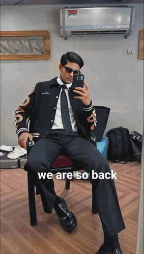A Man In A Suit Is Taking A Picture Of Himself With The Words We Are So Back Below Him GIF
