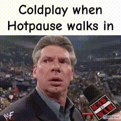 A Man In A Suit Is Talking Into A Microphone While A Crowd Watches . GIF