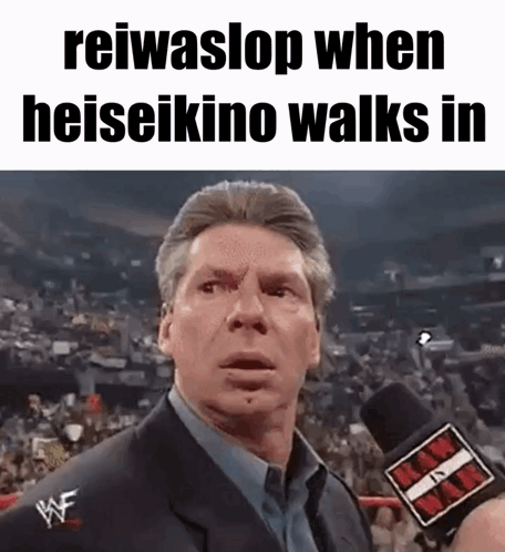 A Man In A Suit Is Talking Into A Microphone While Standing In Front Of A Crowd . GIF