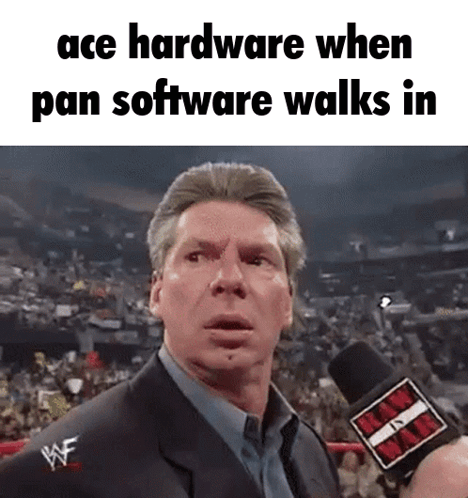 A Man In A Suit Is Talking Into A Microphone With The Words Ace Hardware When Pan Software Walks In . GIF