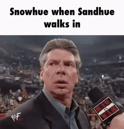 A Man In A Suit Is Talking Into A Microphone With The Words Snowhue When Sandhue Walks In Above Him GIF