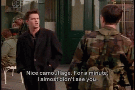 A Man In A Suit Is Talking To A Man In A Camo Jacket GIF