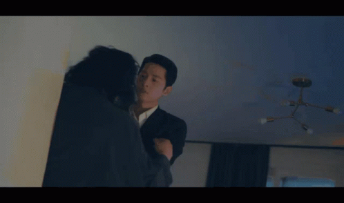 a man in a suit is talking to a woman in a dark room