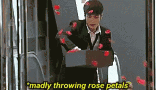 A Man In A Suit Is Throwing Rose Petals At The Camera GIF