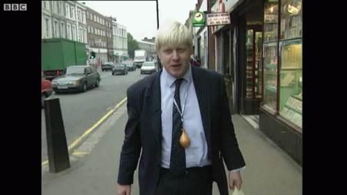 A Man In A Suit Is Walking Down A Street With A Bbc Logo On The Bottom Right GIF