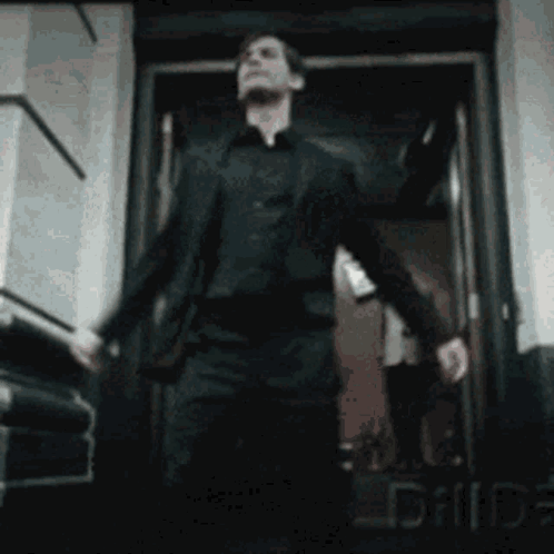 A Man In A Suit Is Walking Out Of A Doorway . GIF