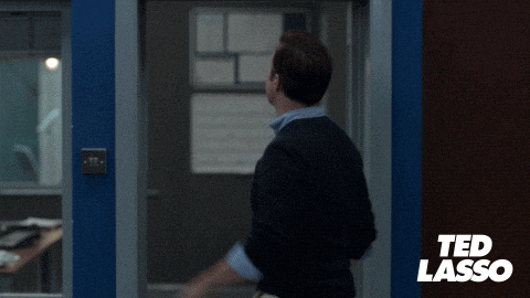 A Man In A Suit Is Waving At A Sign That Says " Believe " GIF
