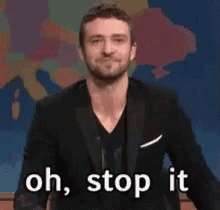 A Man In A Suit Is Waving His Hand And Saying Oh Stop It GIF