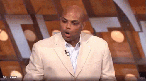 a man in a suit is yawning while standing in front of a microphone on a stage .