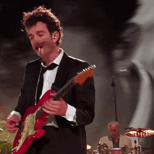 A Man In A Suit Plays A Red Guitar GIF