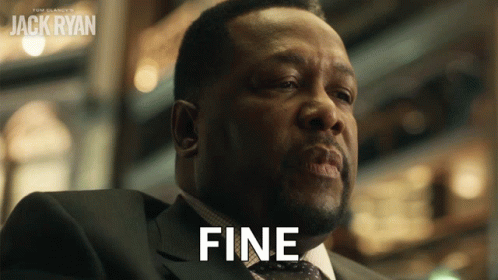 A Man In A Suit Says Fine In Front Of A Poster For Jack Ryan GIF