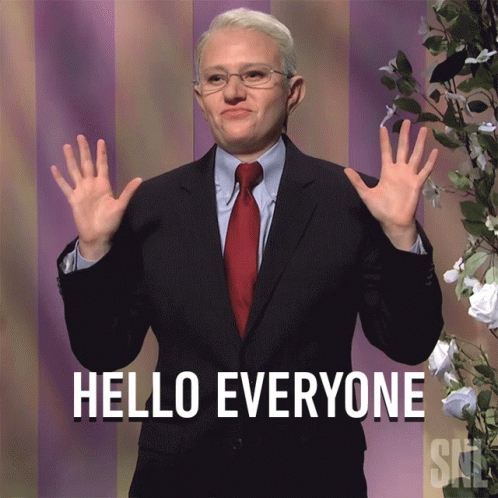 A Man In A Suit Says Hello Everyone With His Hands Up GIF