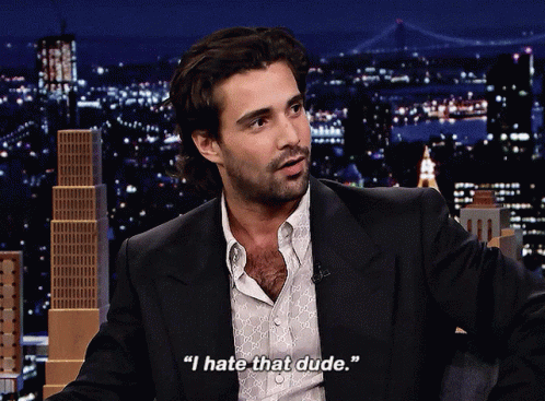 A Man In A Suit Says " I Hate That Dude " In Front Of A City Skyline GIF