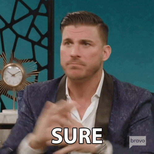 A Man In A Suit Says Sure In Front Of A Bravo Logo GIF