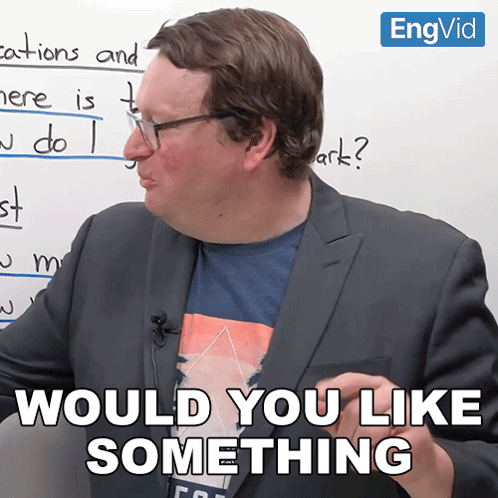 A Man In A Suit Says " Would You Like Something " In Front Of A Whiteboard GIF