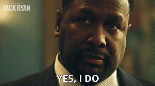 A Man In A Suit Says Yes I Do In Front Of A Poster For Jack Ryan GIF
