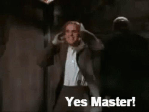 A Man In A Suit Says Yes Master In Front Of A Monster GIF