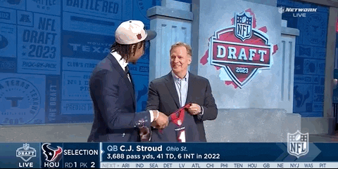 A Man In A Suit Shakes Hands With Another Man In Front Of A Nfl Draft Sign GIF