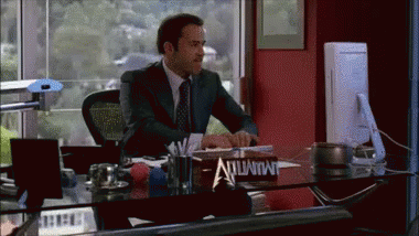 A Man In A Suit Sits At A Desk With A Sign On It That Says Immunity GIF