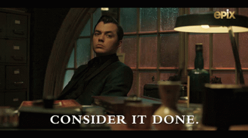 A Man In A Suit Sits At A Desk With The Words " Consider It Done " Above Him GIF