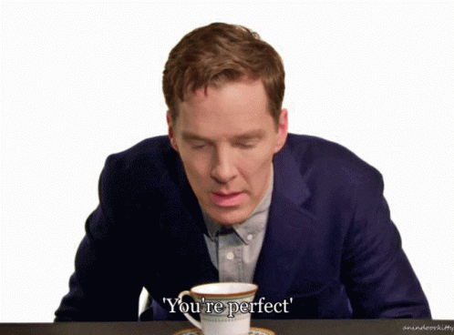 A Man In A Suit Sits At A Table With A Cup Of Coffee And The Words You 'Re Perfect Above Him GIF