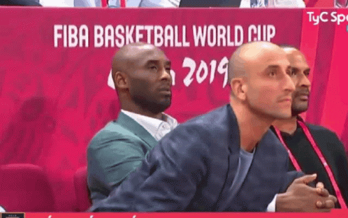 A Man In A Suit Sits In Front Of A Sign That Says Fiba Basketball World Cup 2019 GIF