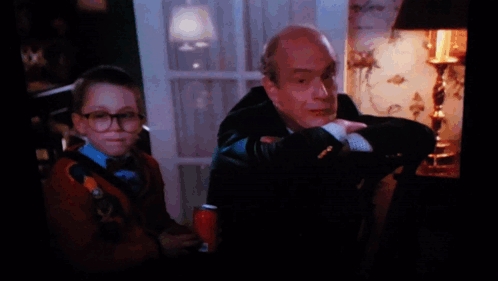 A Man In A Suit Sits Next To A Boy In A Sweater GIF