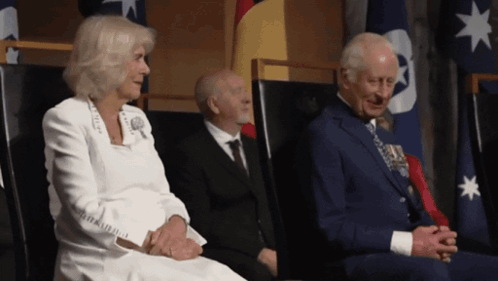 A Man In A Suit Sits Next To A Woman In A White Jacket GIF