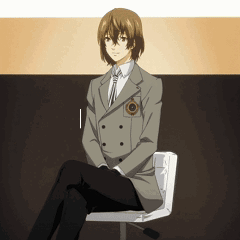 A Man In A Suit Sits On A Chair With His Legs Crossed GIF