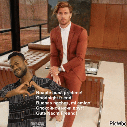 A Man In A Suit Sitting Next To Another Man Who Is Making A Heart With His Hands GIF