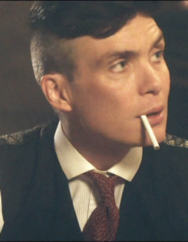 A Man In A Suit Smoking A Cigarette In His Mouth GIF