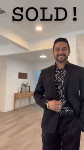 A Man In A Suit Standing In Front Of A Sold Sign GIF