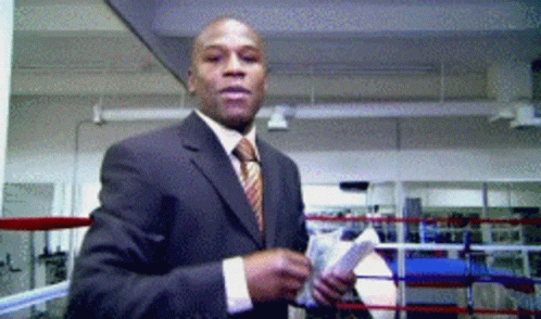 A Man In A Suit Stands In A Boxing Ring GIF