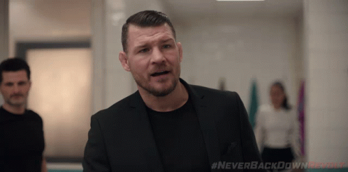 Man In Suit Standing In Hallway With Never Backdown Revolt Text GIF