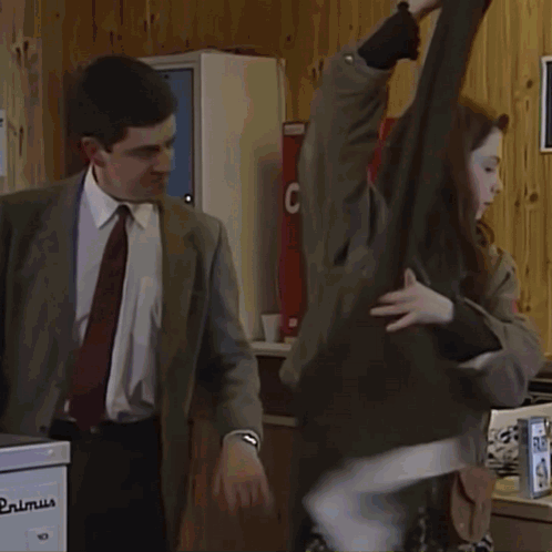 A Man In A Suit Stands In A Laundromat With A Large Wash Sign On The Wall GIF