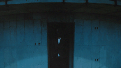 a man in a suit stands in front of a building with the number 11 on the door