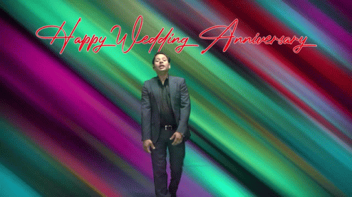 a man in a suit stands in front of a colorful background that says " happy wedding anniversary "